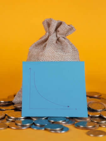 money bag with coins on a yellow backgroundの写真素材