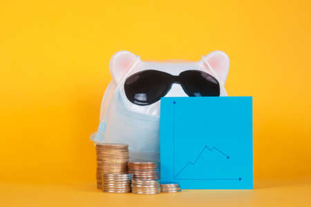 falling financial savings due to a pandemic. masked piggy bank