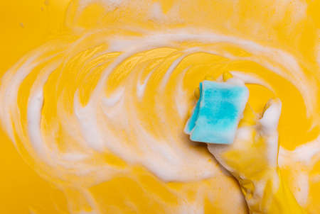 wipe the foam on a yellow background with a blue gloved sponge.の写真素材