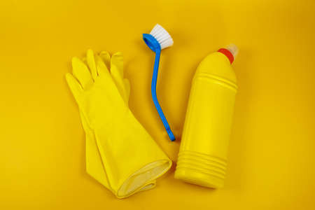 Bottle with detergent powder and brushes and yellow gloves on yellow background, space for textの写真素材