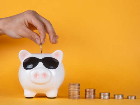 Piggy bank with hand on a yellow background. coinsの写真素材