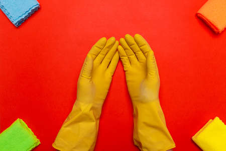 hands in yellow rubber gloves in the center around a rag on a red background.の写真素材