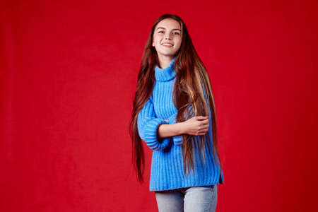 beautiful girl in a warm sweater on a red background.の写真素材