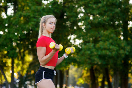A young woman goes in for sports outdoors. girl with blond hair is training in the park on the nature.の写真素材