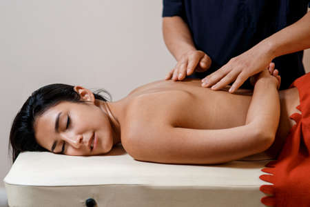 A young woman gets a massage procedure. Masseur makes back massageの写真素材