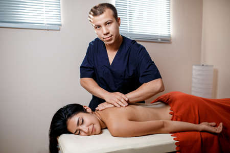 A young woman gets a massage procedure. Masseur makes back massageの写真素材