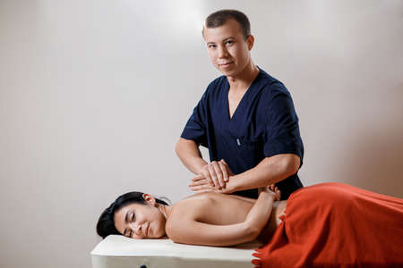 A young woman gets a massage procedure. Masseur makes back massageの写真素材
