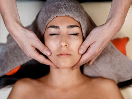 Face massage. Close-up of young woman getting spa massage treatment at beauty spa salon.Spa skin and body care. Facial beauty treatment.Cosmetologyの写真素材