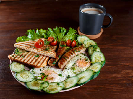 Blush sandwiches with sausages, dill and a sprig of basil on a white plate on a wooden table. The idea of fast cooking. Close up.の写真素材