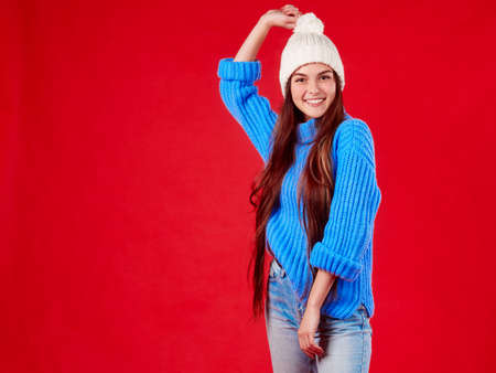 beautiful girl in a sweater and a hat on a red background.の写真素材