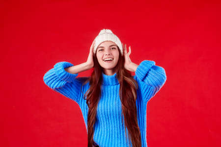 beautiful girl in a sweater and a hat on a red background.の写真素材