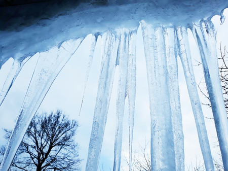 Huge icicles against the blue sky and trees