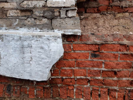 Destroyed gray plaster on a red brick wall. Background