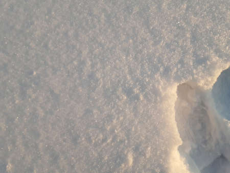 Snow texture snowdrift in side lighting. Falling small snowflakes in backlighting. For background....