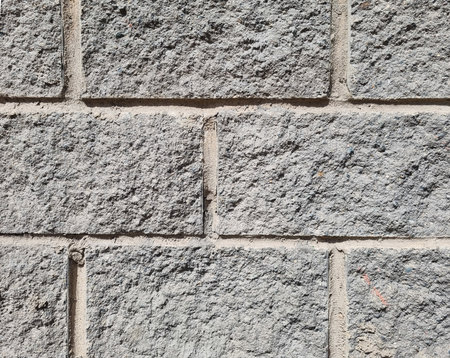 Granite surface texture, background. The wall is made of gray stone blocks.