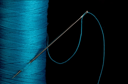 Blue thread with needle against a black backgroundの写真素材
