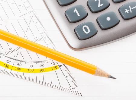 close-up of protractor, calculator, and pencil on paper