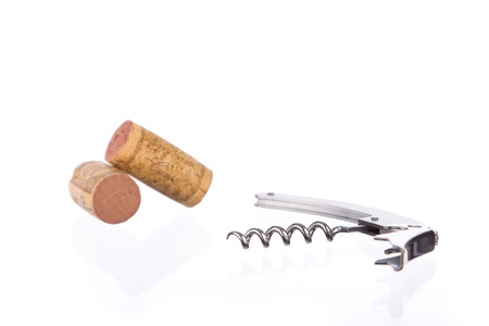 metal corkscrew and two corks on a reflective surface against whiteの写真素材