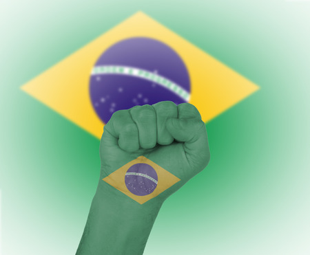 Fist wrapped in the flag of Brazil and flag in the backgroundの写真素材