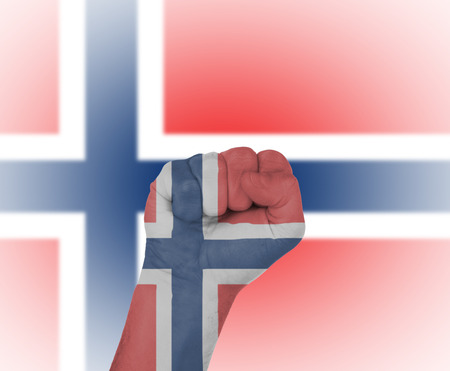 Fist wrapped in the flag of Norway and flag in the backgroundの写真素材