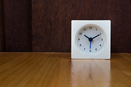 The white alarm clock on dark wooden background.の写真素材