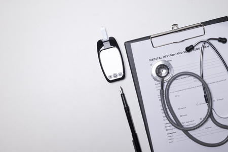 doctor desktop with stethoscope, clipboard with medical records form.の写真素材