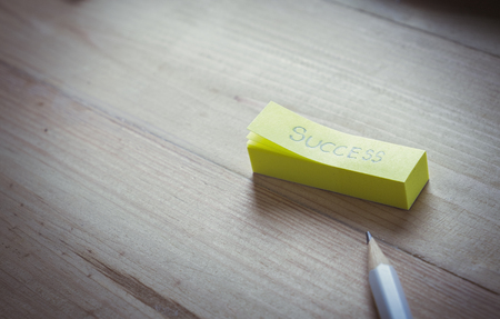 Hand writing word %u201CSUCCESS%u201D in note on wooden background. Copyspace of successful concept.の写真素材