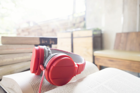 Red headphone on book in cafe or library. Soft focus and soft sunlight in the morning feel relax.の写真素材