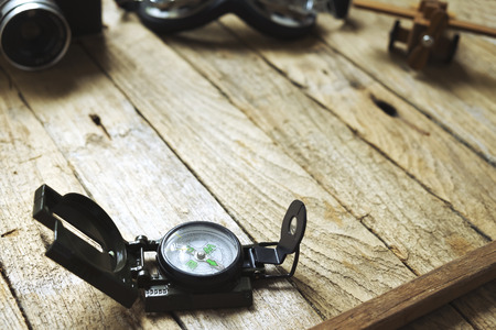 Compass on wooden background. Blur vintage camera, glasses and balsa wood model airplane. Vintage filter, travel concept.の写真素材