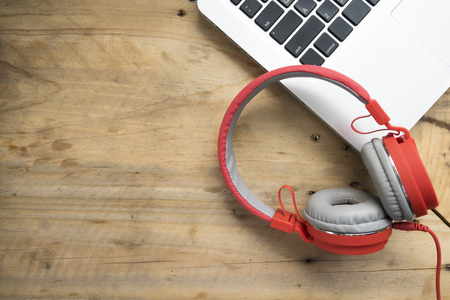 Red headphones and computer laptop on wood table.の写真素材