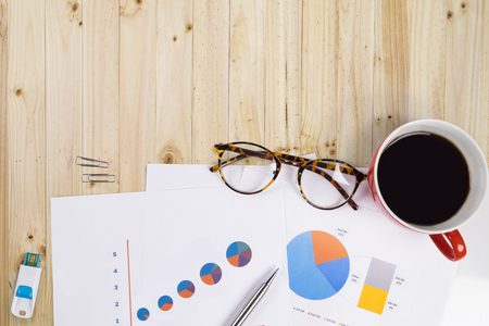 View from above of office supplies and red cup of coffee on a vintage retro wooden working table background.の写真素材
