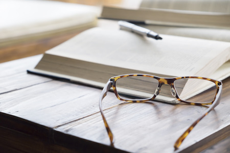glasses on opening book in library or cafe
