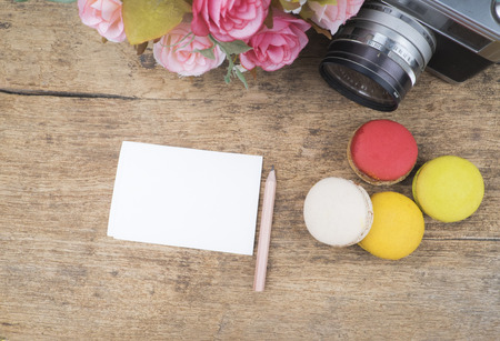 Empty note paper ,macaroons flower and vintage camera on wooden backgroundの写真素材