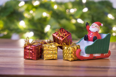Christmas concept, toy santa sleigh,  gift boxes on wooden floor and blur green and light bokeh
