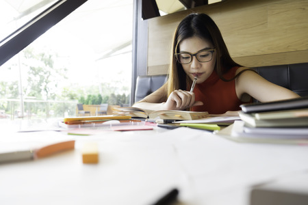 Collegian woman reading book in library. Education idea concept. Reading and researching for exam. The student life.の写真素材