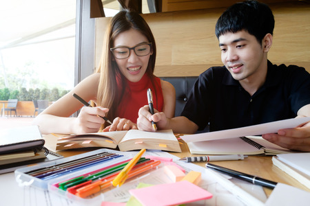 Young woman and man studying for a test/ an exam. Tutor books with friends. Young students campus...