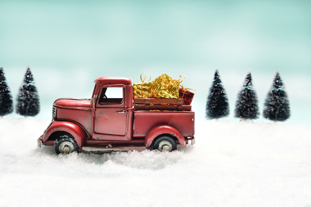 Red truck toy carrying a christmas gift on sweet pastel retro turquoise color background.の写真素材