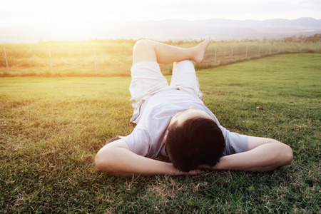 Relaxation man lay down on grass and sunlight in the summer day. Relaxing concept.の写真素材