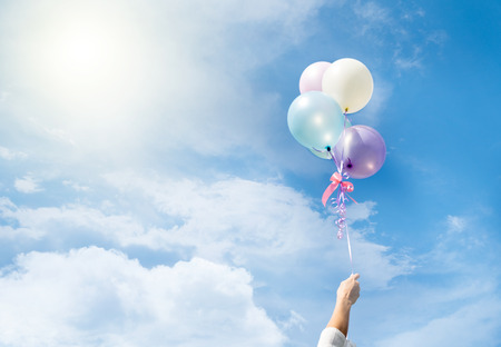 Girl hand holding multicolored balloons done with a retro vintage instagram filter effect, concept of happy birth day in summer and wedding honeymoon party (Vintage color tone)の写真素材