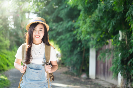 woman traveler with backpack with hat and looking at nature and forest, travel concept, space for text, atmosperic epic moment, hipster and vintage effect.の写真素材