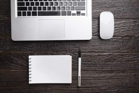 Copyspace of top view of computer laptop,mouse, pen and empty page of white notebook on wooden working table.の写真素材