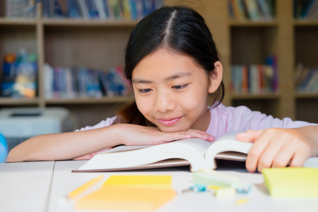 Education Concept. School girl reading book in library.の写真素材