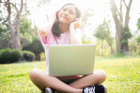Relax and listen music concept. Girl with wireless headphones listens to the music in park.の写真素材