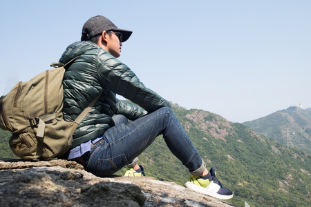 Young backpacker enjoying a valley view from top of a mountain.の写真素材