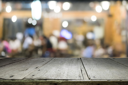 Empty wooden table for present product on coffee shop or soft drink bar blur background with bokeh...
