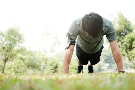 Sport fitness man push-ups. Male athlete exercising push up outside in sunny sunshine. Fit male fitness model in crossfit exercise outdoors. Healthy lifestyle conceptの写真素材