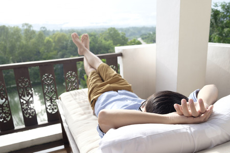 Man relaxing in his chair and enjoying the view from terrace.の写真素材