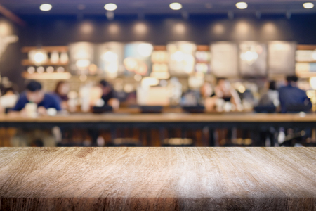 Empty wooden table for present product on coffee shop or soft drink bar blur background with bokeh image.の写真素材