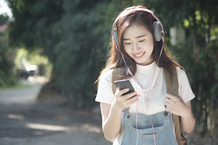 Woman walk in the park outdoor and listening to the music media entertainment. Relaxation concept. Soft picture for feeling relax with easy listening musicの写真素材