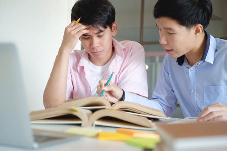 Young woman and man studying for a test or an exam. Tutor books with friends. Young students campus helps friend catching up and learning. People, learning, education and school concept.の写真素材